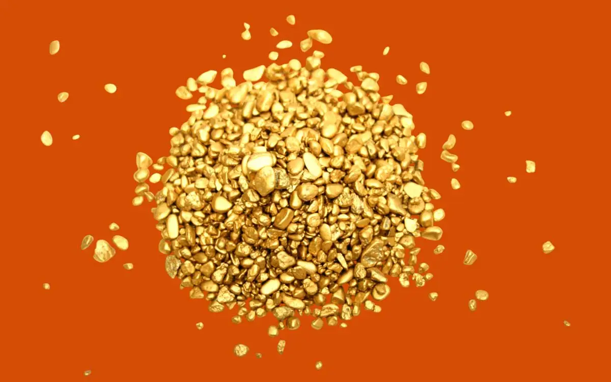 Ein Haufen feiner Gold-Nuggets oder Gold-Granulat (Industriegold) vor einem kräftigen orangefarbenen Hintergrund.